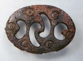 FIB-41773 - Fibule à décor de trompettes simplifiéesbronzeBroche ovale, plate, découpée de plusieurs ajours évoquant le motif en trompettes ; cercles oculés dans les intervalles.