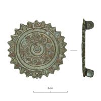 FIB-41922 - Fibule circulaire émailléebronzeFibule à charnière réduite sous l'arc. Arc circulaire à bord dentelé décoré de cercles concentriques et de motifs émaillés complexes.