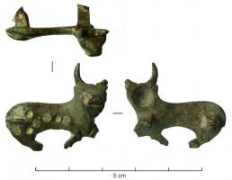 FIB-4368 - Fibule zoomorphe : taureaubronzeBroche représentant un taureau couché à droite, la tête, en ronde-bosse, tournée vers le spectateur, le corps recouvert de pastilles d'émail.