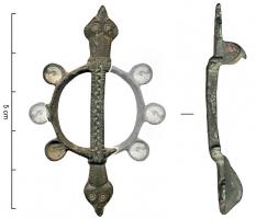 FIB-4904 - Fibule symétrique émailléebronzeFibule composée d'une couronne mince, avec 6 disques émaillés sur le pourtour, traversée par une bande axiale ornée d'une ligne ondulée entre deux séries d'incisions transversales ; terminaisons symétriques en têtes de reptiles.