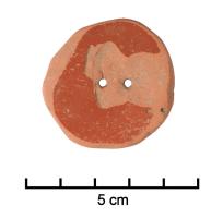 IND-4307 - Disque à double perforationterre cuiteObjet retaillé dans un fragment de vase en terre cuite, de forme grossièrement circulaire et percé de deux trous vers le centre.