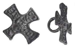 SIG-4097 - Signaculum cruciformebronzeTPQ : 300 - TAQ : 500Signaculum en forme de croix latine, éventuellement pattée ; lettres rétrogrades et en relief dans un cadre en relief (alphabet grec ou latin) ; anneau de préhension au revers.