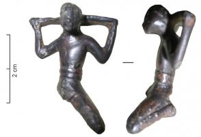 STE-3017 - Statuette : captif ?bronzeFigurine d'homme agenouillé, jambes écartées, la taille serrée d'une large ceinture; les mains sont relevées et sans doute attachées à une barre transversale (carcan ?) passant derrière la tête.