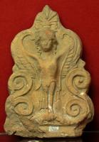 ANT-4027 - Antéfixe : Sirèneterre cuiteAntéfixe dont la façade comporte une figure monstrueuse (oiseau à tête de femme : Sirène), encadrée par deux paires de volutes d'une palmette, dont les branche ssupérieures sont remplacées par les ailes, et surmontée d'une palmette axiale.