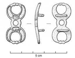 APT-4025 - Applique à tenons en T, type B5bronzeApplique pourvue au revers de 2 tenons en T, normalement guillochés sur la partie extérieure de la barrette ; l'objet est percé transversalement et un anneau retenu par un crampon replié à l'arrière y joue librement. Ce type présente une forme symétrique autour de l'anneau central, avec des extrémités formées de deux lunules bouletées, creusées de trois loges d'émail (rectangle au centre).