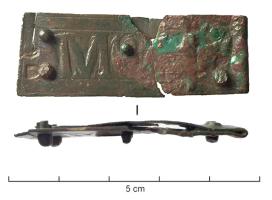 BAC-8002 - Boucle à chape inscritebronzeBoucle à chape de tôle rectangulaire allongée, fixée à l'arrière par des rivets, avec un décor estampé comprenant une inscription  en lettres gothiques.