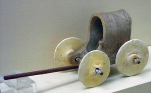 CHM-1001 - Char miniatureterre cuiteChar miniature modelé en argile, avec une caisse fermée en berceau, ornée de motifs incisés; les roues pleines sont rapportées et mobiles.