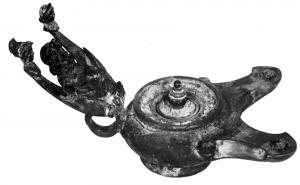 LMP-4010 - Lampe à deux becs et bustesbronzeLampes à deux becs, dont le réflecteur en forme de croissant porte les bustes divins de la Triade Capitoline : Minerve, Jupiter et Junon ; trou de remplissage centré, avec un couvercle à bouton.