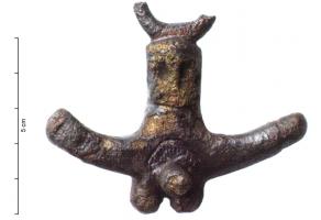 PDH-4029 - Pendant de harnais phalliquebronzePendant de harnais à anneau coulé, d'un type classique avec ses parties génitales masculines au repos, encadrées d'un côté d'un phallus et de l'autre d'une main faisant le geste de la figue; mais entre l'élément central et l'anneau de suspension apparaissent les traits d'un visage humain.